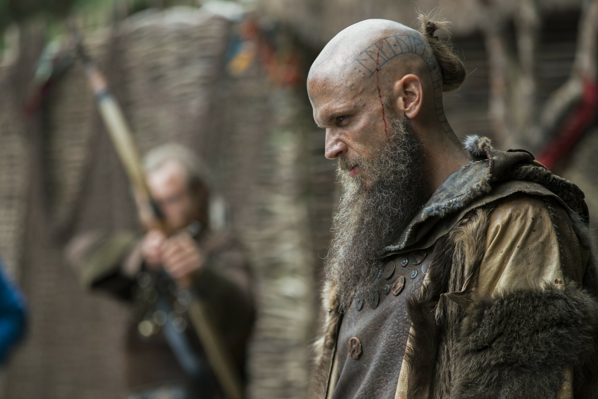 8K Ultra HD desktop wallpaper featuring a scene from the TV show Vikings (2013) with a focused warrior in detailed period attire and a blurred figure in the background.