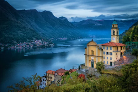 Stunning 4K Ultra HD view of Lake Como, Italy, featuring a historic church and charming lakeside town nestled among mountains at dusk.