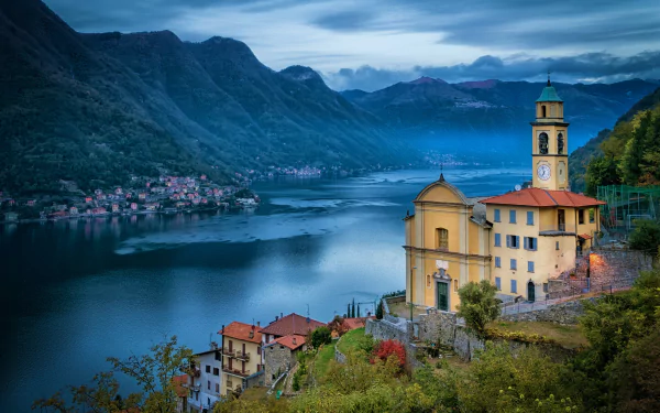 Stunning 4K Ultra HD view of Lake Como, Italy, featuring a historic church and charming lakeside town nestled among mountains at dusk.