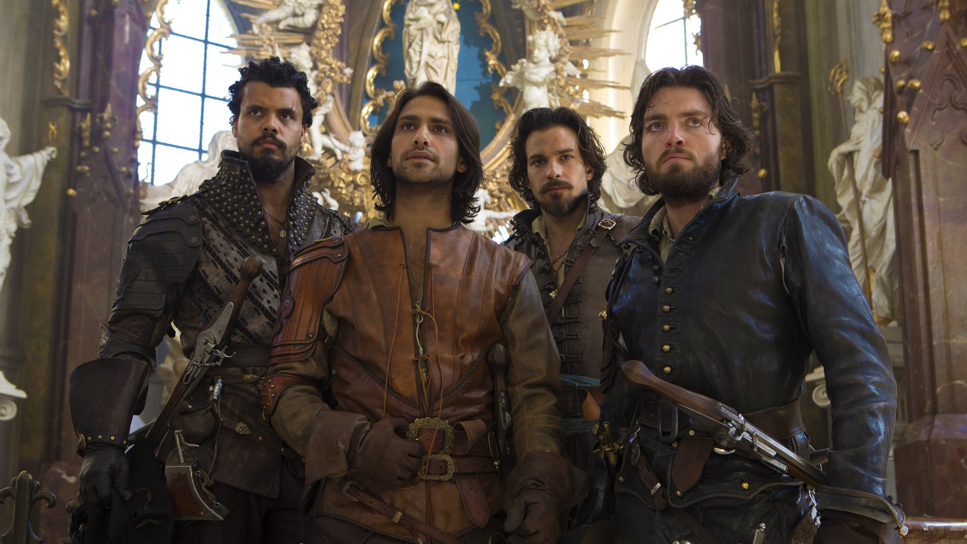 4K Ultra HD desktop wallpaper featuring the main cast of the TV show The Musketeers in period costumes inside an ornate, historic setting.