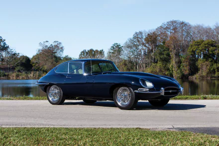 Black Jaguar E-Type parked by a lakeside road with trees and clear sky in the background, captured in HD for a PC desktop wallpaper.