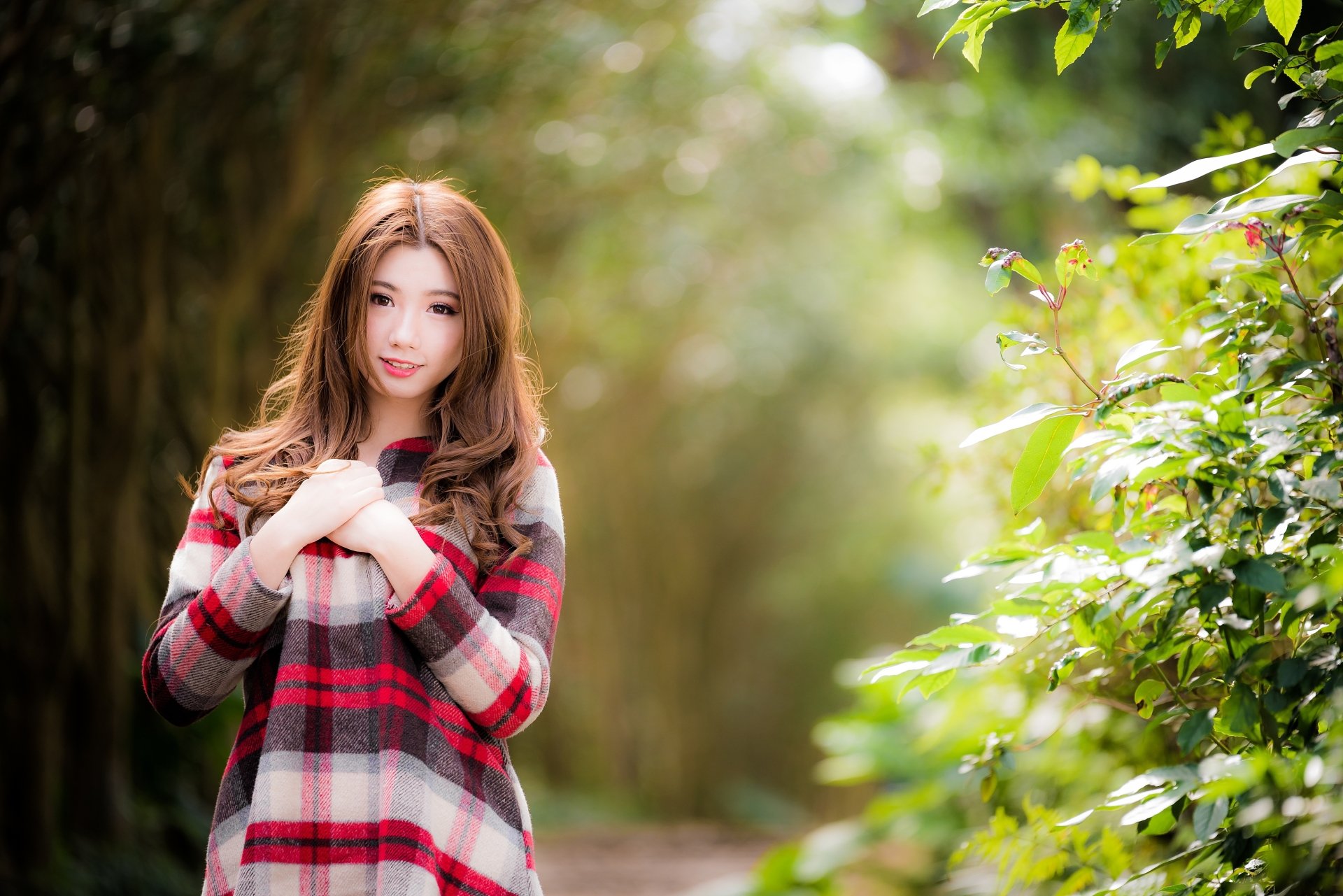 Brunette woman model smiling in a shallow depth-of-field outdoor scene with soft bokeh foliage — 4K Ultra HD PC desktop wallpaper/background.