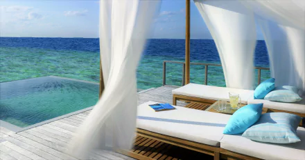 4K Ultra HD PC desktop wallpaper: resort deck with sheer curtains, cushioned daybeds by a man-made infinity pool blending into the turquoise sea and ocean horizon.