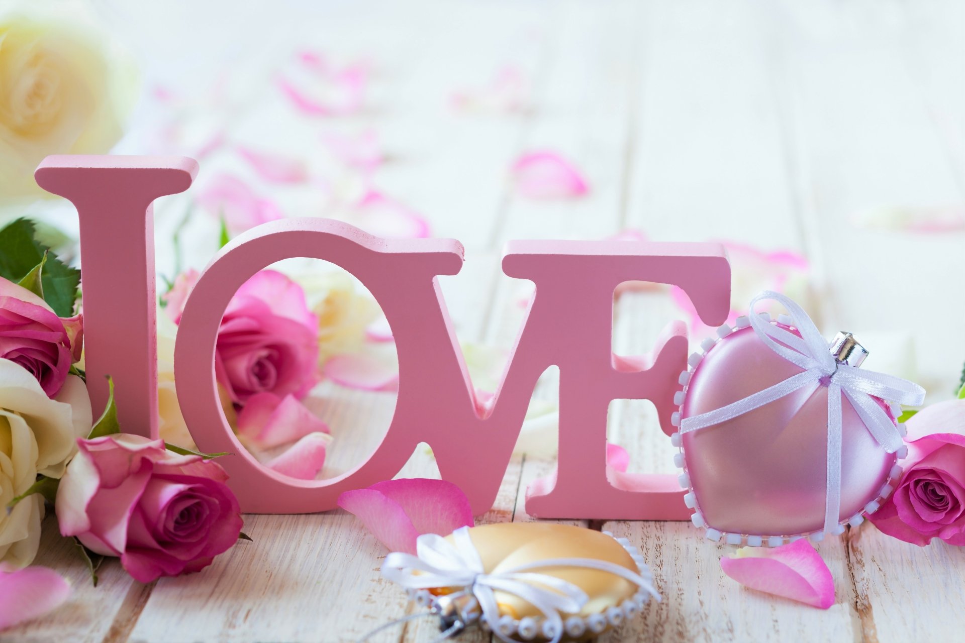 A 4K Ultra HD PC desktop wallpaper featuring an artistic wooden LOVE word surrounded by pink roses and a heart-shaped gift, symbolizing romance and affection.