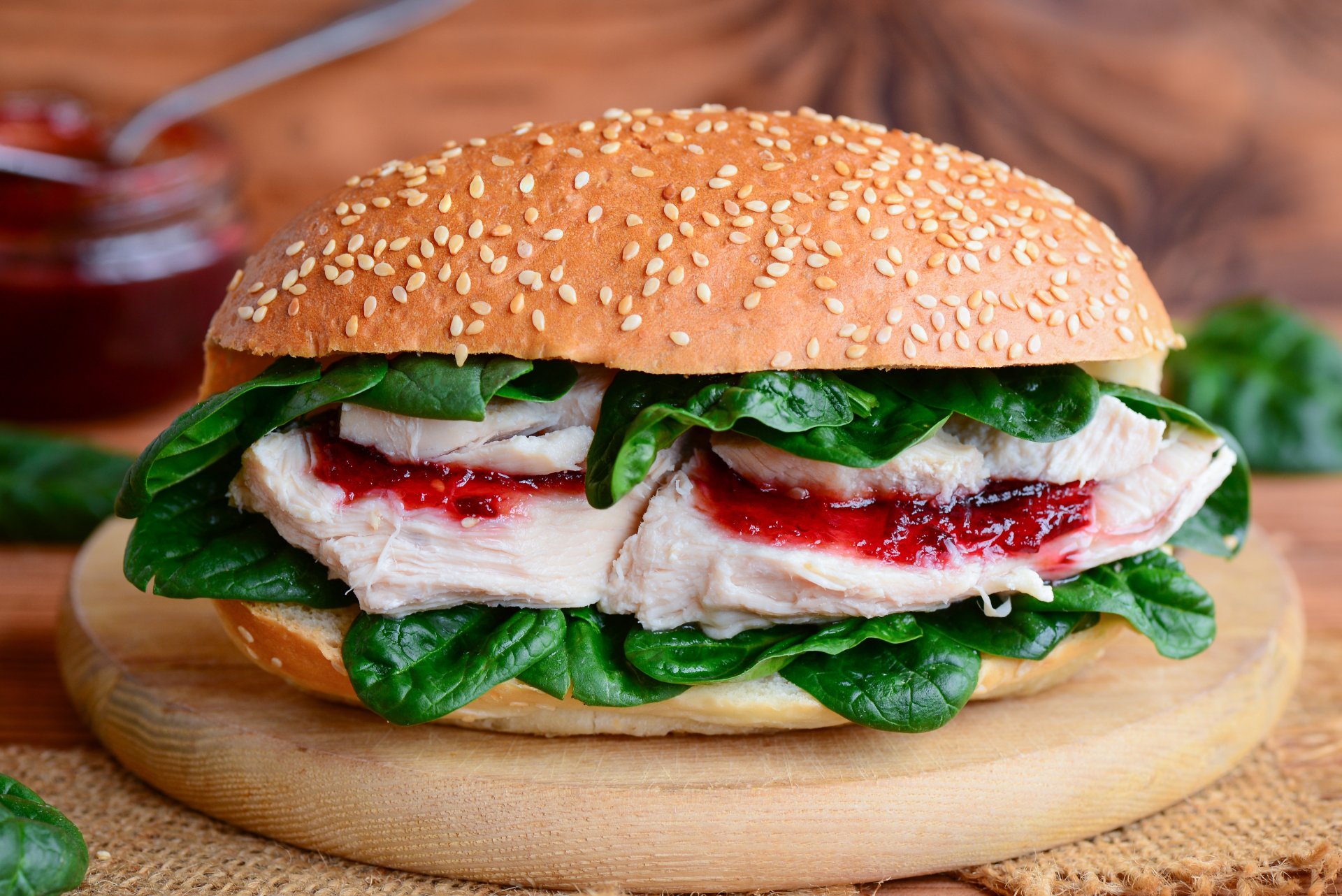 Close-up of a fresh burger with leafy greens and sliced turkey on a sesame seed bun, presented as a vibrant 4K Ultra HD PC desktop wallpaper.