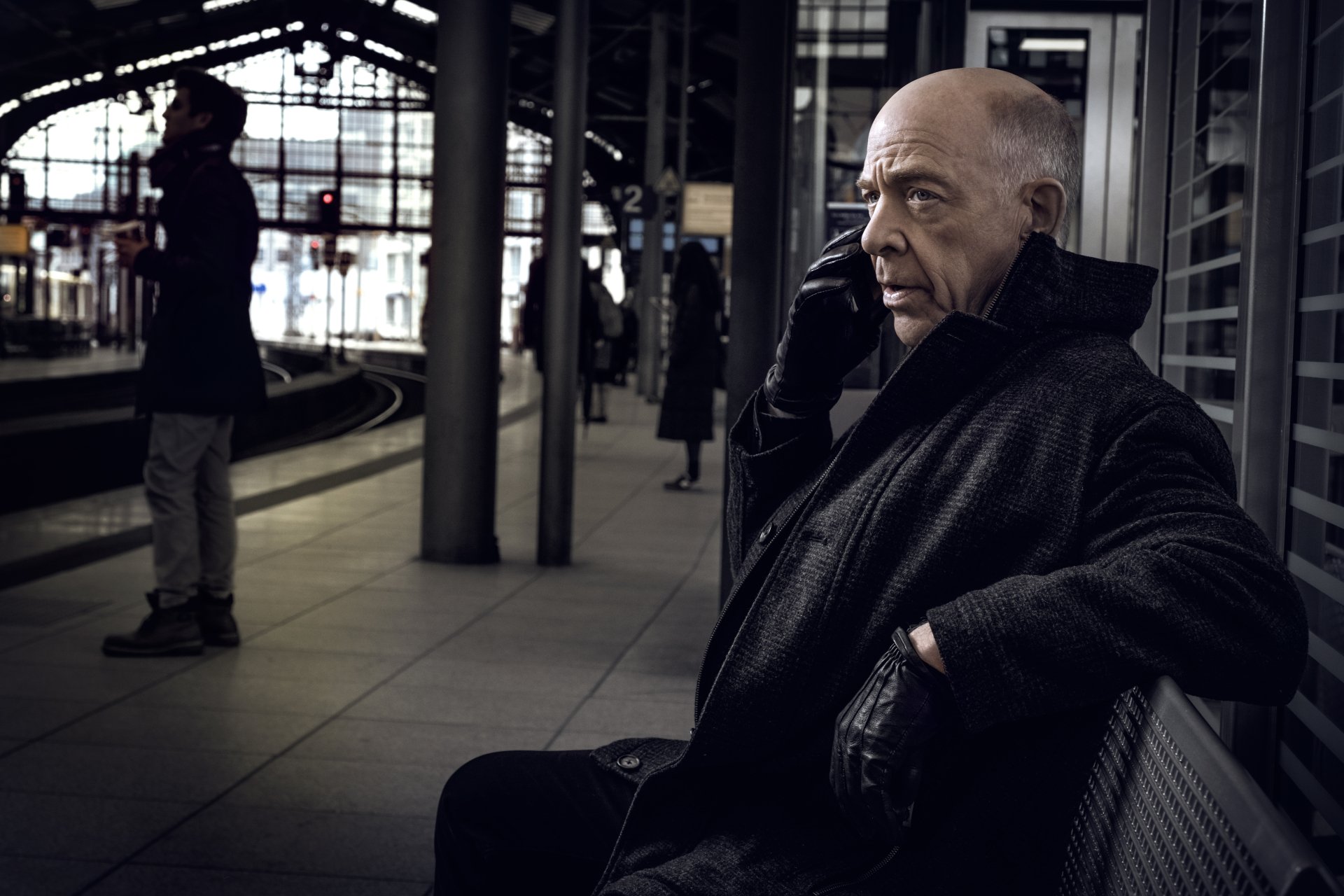 HD desktop wallpaper featuring a scene from Counterpart with a man on a phone at a train station.