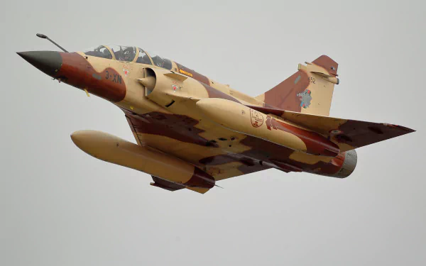 HD desktop wallpaper featuring a Dassault Mirage 2000 military jet fighter warplane in flight against a gray sky.