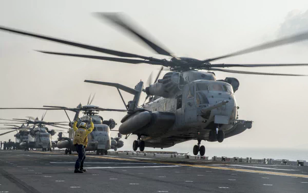 Military Sikorsky CH-53 Sea Stallion helicopters hover above an aircraft carrier deck with personnel directing operations in this HD desktop wallpaper background.
