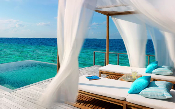 Turquoise tropical ocean and horizon view from a resort deck featuring white curtains and lounge chairs, captured in an HD PC desktop wallpaper background.