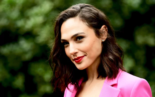 HD desktop wallpaper featuring Israeli actress and model Gal Gadot with brunette long hair, brown eyes, bright lipstick, and a warm smile against a blurred natural background.