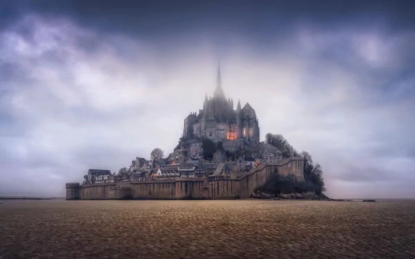 HD wallpaper of Mont Saint-Michel, a historic religious monastery town in France, surrounded by tidal sands under a dramatic sky.