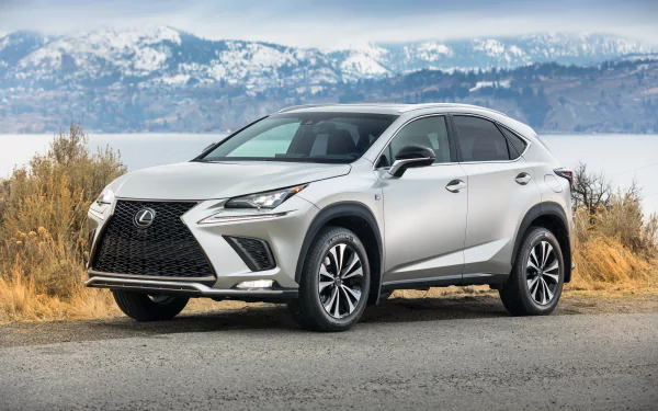 Silver Lexus NX SUV parked on a roadside by a lake with snow-capped mountains — 4K Ultra HD PC desktop wallpaper background.