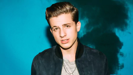 HD desktop wallpaper featuring a portrait of Charlie Puth against a blue, smoky background.