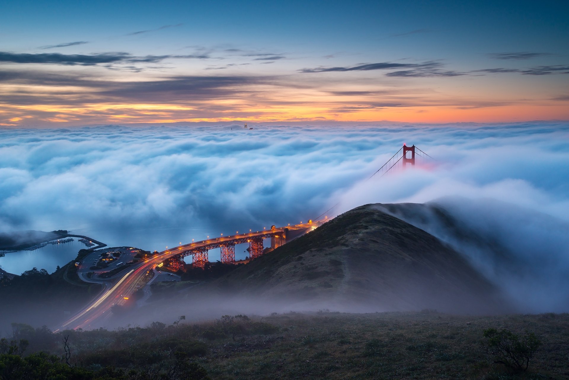 HD PC desktop wallpaper featuring the Golden Gate Bridge emerging through clouds at the horizon during sunset, showcasing the iconic man-made structure.