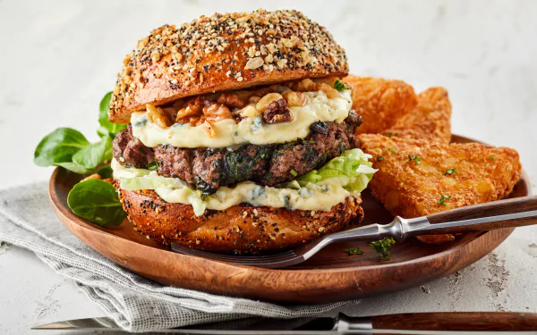 5K Ultra HD PC desktop wallpaper: food, burger — seeded bun stacked with a beef patty, melted cheese, greens and creamy slaw, served with crispy hash browns on a wooden plate.