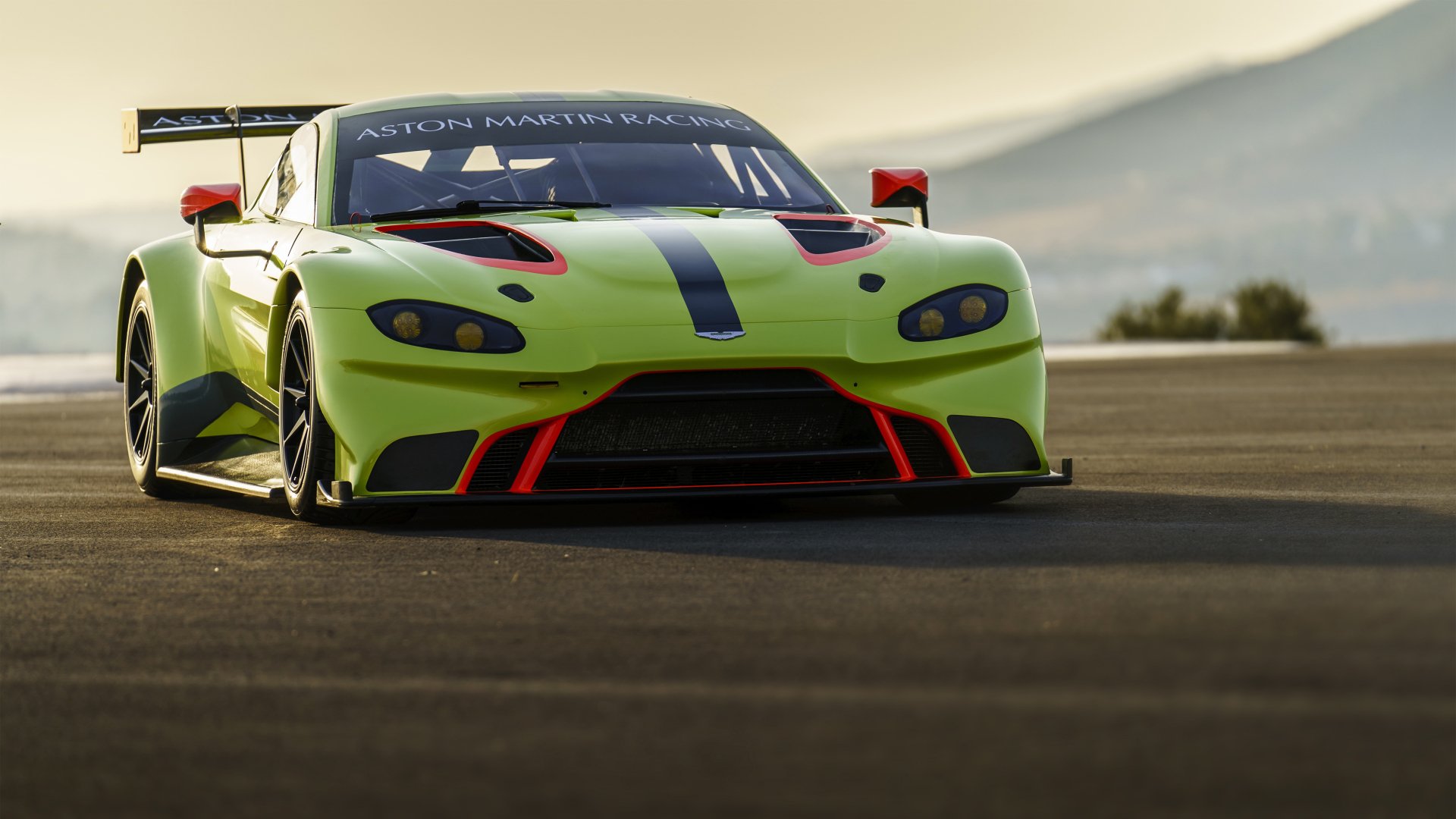 Front view of neon green Aston Martin Vantage GTE race car on track at sunset, high-detail 5K Ultra HD PC desktop wallpaper background.