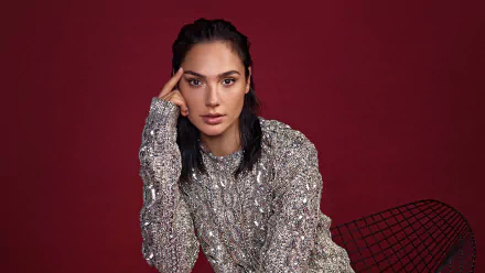 Portrait of Israeli actress Gal Gadot with black hair and brown eyes, wearing a textured silver sweater against a deep red background in 4K Ultra HD quality.