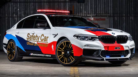 BMW M5 MotoGP Safety Car in white, red and blue livery with rooftop lights and gold rims, photographed as a 4K Ultra HD PC desktop wallpaper background.