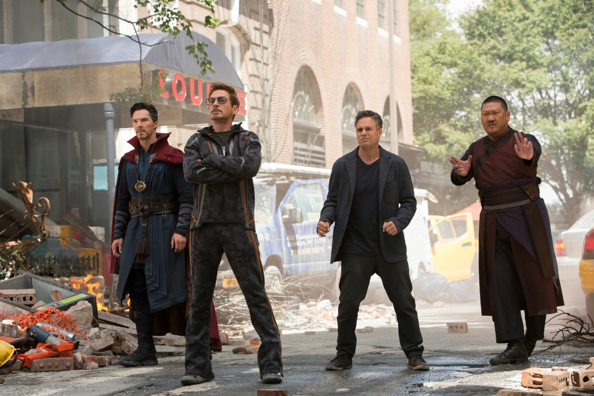 HD wallpaper from Avengers: Infinity War featuring Doctor Strange, Tony Stark, Bruce Banner, and Wong standing in a city street amidst debris.