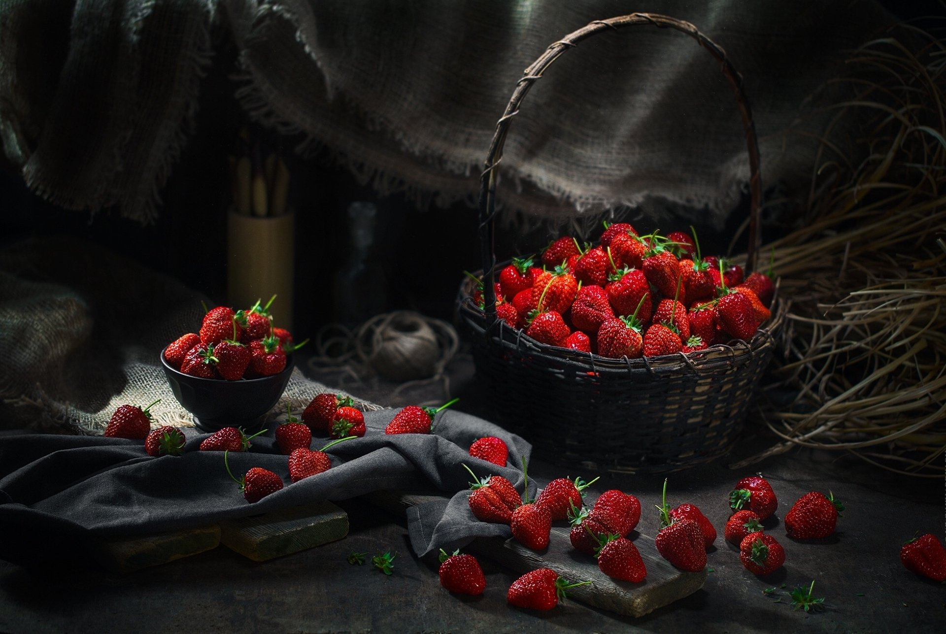 HD still life desktop wallpaper featuring a basket and bowl filled with fresh strawberries, scattered fruit, and a dark, moody background for a rich visual impact.