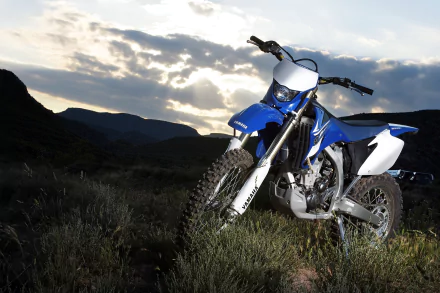 Blue Yamaha WR450F off-road motorcycle parked on grassy terrain with dramatic hills and sunset — 4K Ultra HD PC desktop wallpaper and background.
