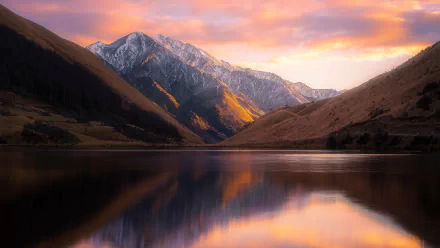 HD desktop wallpaper showcasing a tranquil lake and mountain landscape during a stunning sunset in New Zealand. The scene features vibrant colors and reflects the serene beauty of nature.