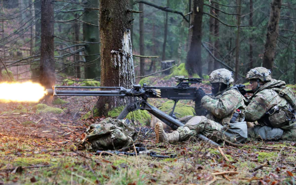 HD desktop wallpaper showing soldiers in military gear firing a machine gun weapon in a dense forest setting.