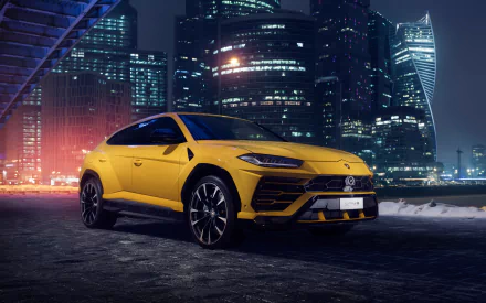 Yellow Lamborghini Urus parked on a city street at night with illuminated skyscrapers in the background, displayed as a 4K Ultra HD PC desktop wallpaper.