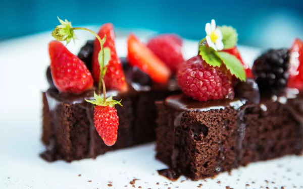 Close-up of rich brownie squares topped with fresh strawberries, raspberries, and edible flowers, captured in stunning 4K Ultra HD for a vibrant dessert wallpaper.