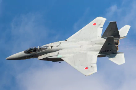 Mitsubishi F-15J jet fighter warplane in flight against a clear blue sky, showcasing its sleek military aircraft design.