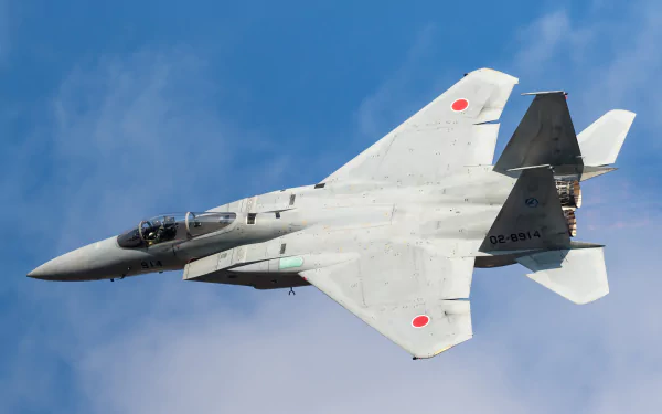 Mitsubishi F-15J jet fighter warplane in flight against a clear blue sky, showcasing its sleek military aircraft design.