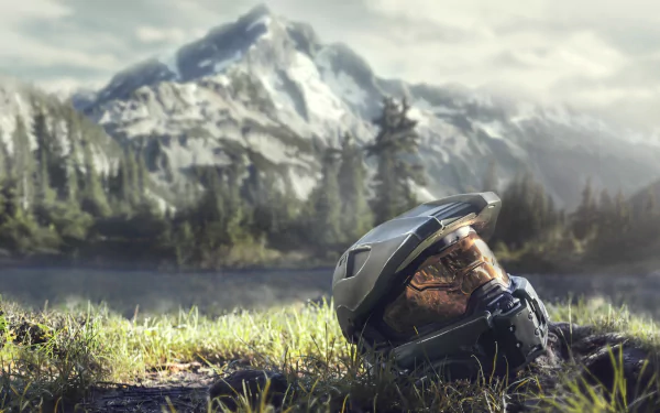 HD wallpaper featuring Master Chief's helmet from the video game Halo Infinite, set against a stunning mountainous landscape with lush greenery and a serene lake.
