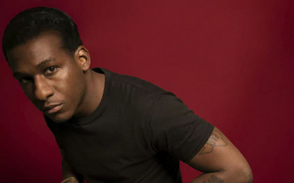 HD desktop wallpaper featuring a man with a serious expression, wearing a black shirt against a red background.