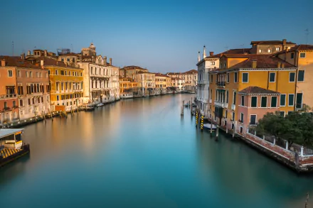 Panoramic view of Venice’s Grand Canal, Italy, showcasing historic buildings lining the man-made waterway under a clear sky in 4K Ultra HD quality.