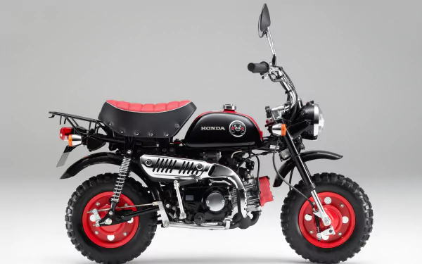 Black-and-red Honda Monkey mini motorcycle (vehicle) on a neutral gray studio backdrop — 2K Quad HD PC desktop wallpaper and background.