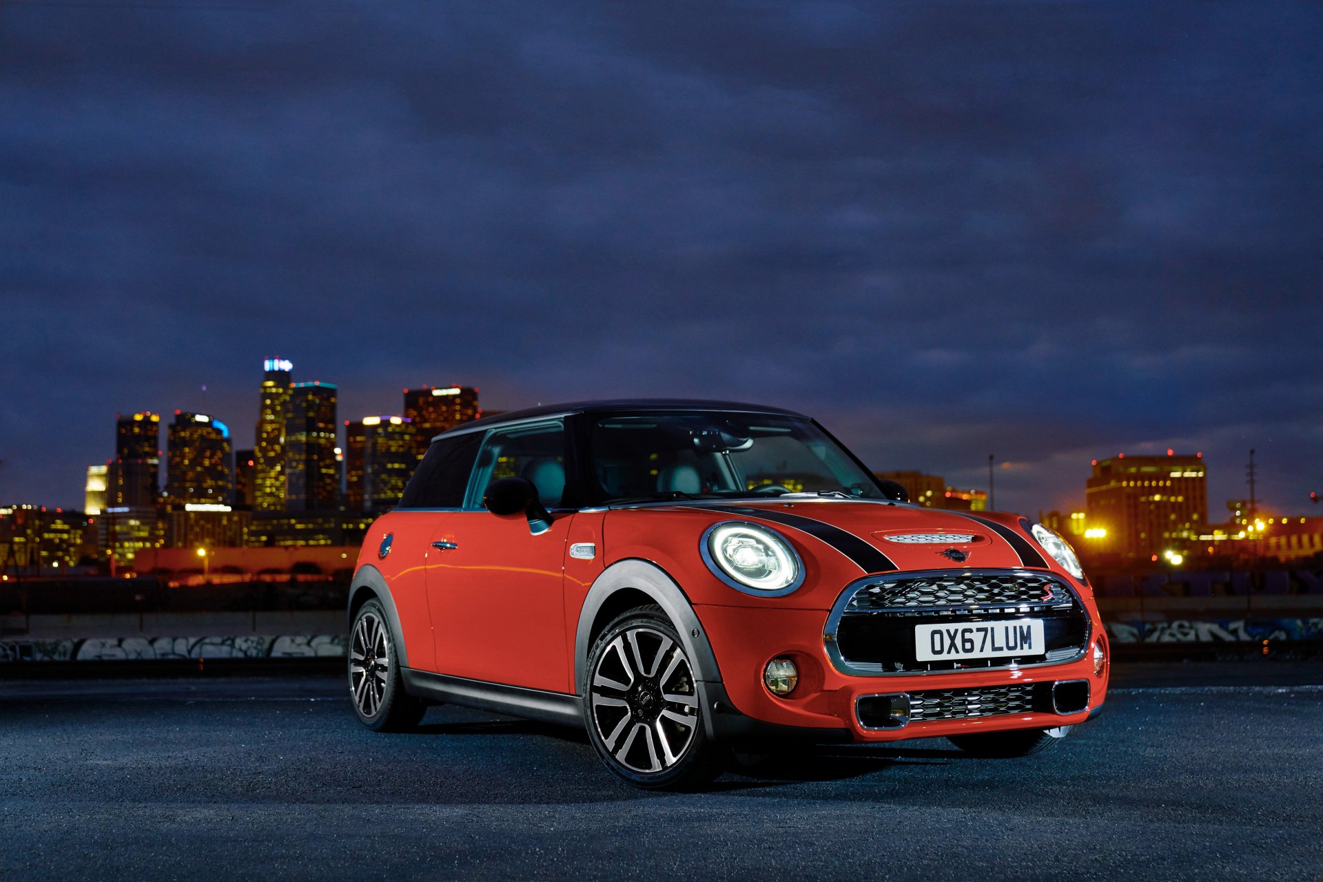 Red Mini Cooper S compact car on an urban waterfront at dusk with illuminated skyline — 4K Ultra HD PC desktop wallpaper background.