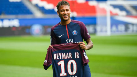 Brazilian soccer star Neymar Jr. holds his Paris Saint-Germain F.C. jersey with the number 10 in a vibrant HD desktop wallpaper background.