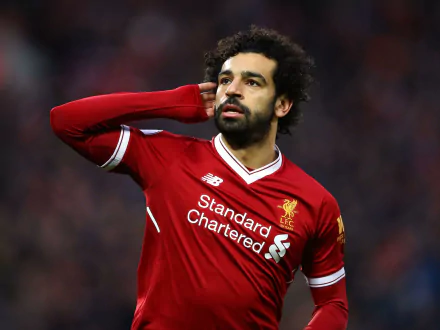 HD desktop wallpaper of Egyptian soccer star Mohamed Salah in Liverpool kit, captured during a match with a focused expression in a sports setting.
