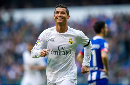 HD wallpaper of Portuguese soccer player Cristiano Ronaldo in a white Real Madrid jersey, smiling during a match. Other players and the crowd can be seen in the background.
