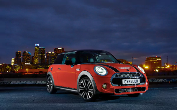 Red Mini Cooper S compact car on an urban waterfront at dusk with illuminated skyline — 4K Ultra HD PC desktop wallpaper background.
