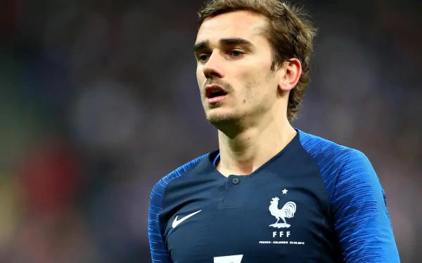 Portrait of a male soccer player in a France national team kit against a blurred stadium — 2K Quad HD PC desktop wallpaper and sports background.