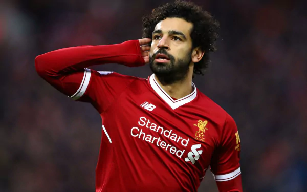HD desktop wallpaper of Egyptian soccer star Mohamed Salah in Liverpool kit, captured during a match with a focused expression in a sports setting.