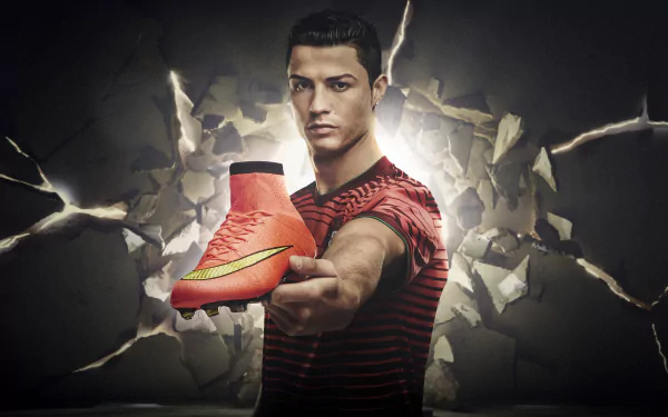 Cristiano Ronaldo holding a soccer cleat against a dramatic cracked wall background. HD desktop wallpaper, showcasing the Portuguese soccer icon.