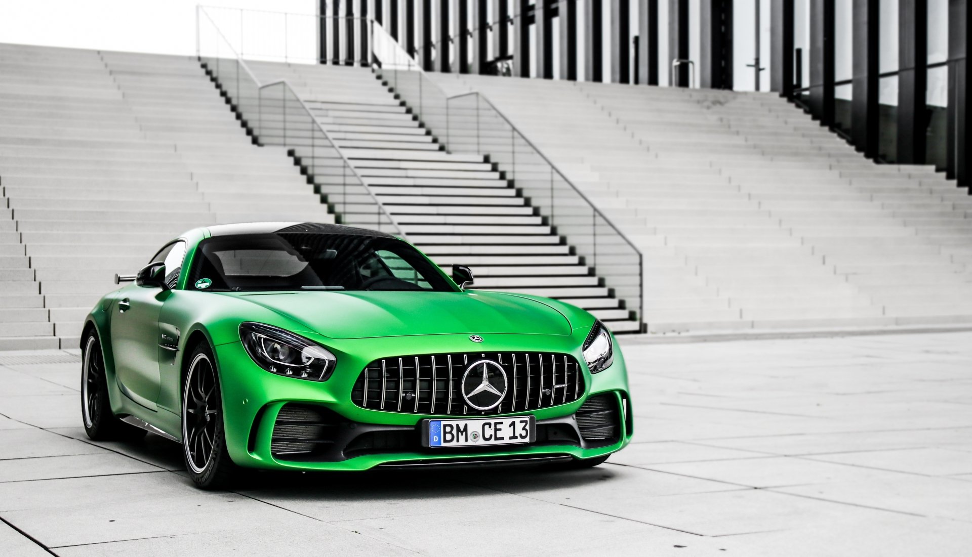 Green Mercedes-AMG GT supercar parked before concrete steps, high-contrast 4K Ultra HD desktop wallpaper of a Mercedes-Benz performance vehicle.