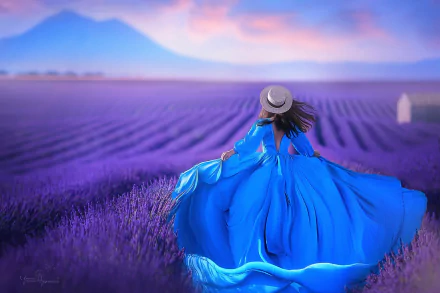 A woman in a flowing blue dress and straw hat stands in a vast lavender field under a pastel sky, creating an artistic and serene HD desktop wallpaper.