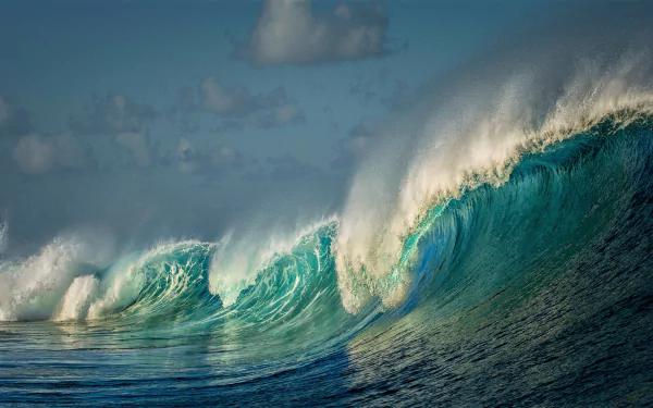 HD desktop wallpaper featuring a breathtaking turquoise ocean wave crashing under a sky with scattered clouds, showcasing the beauty of nature.