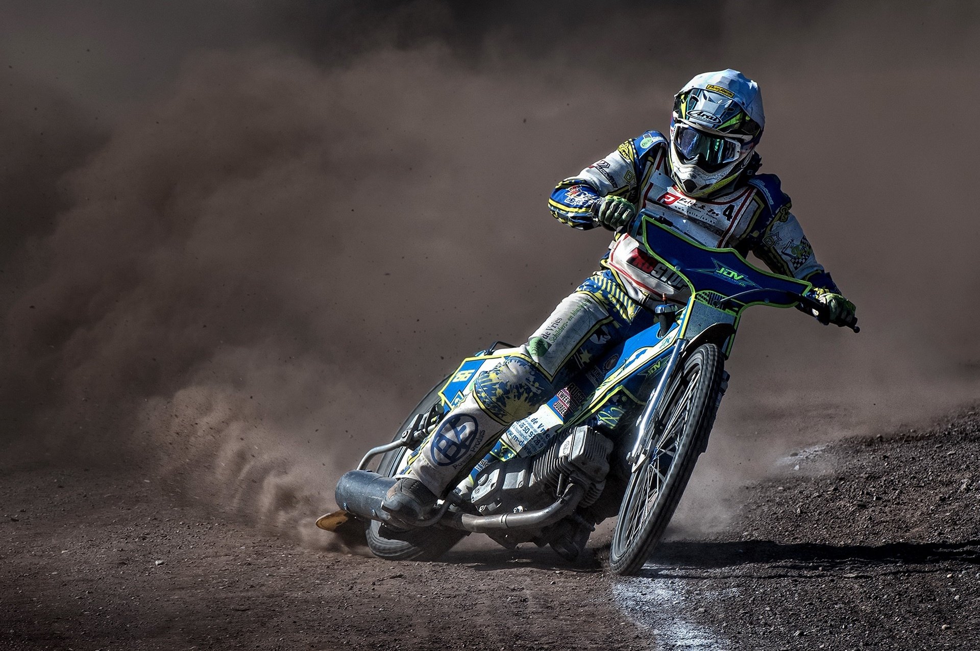 HD PC desktop wallpaper of a motocross rider on a motorcycle racing a dirt track, leaning into a turn and kicking up dust.