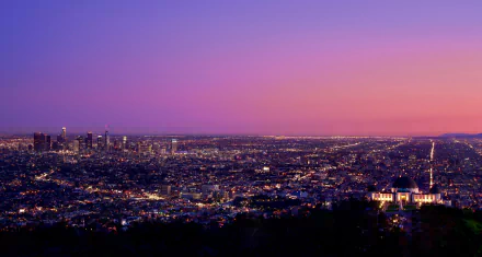 4K Ultra HD view of Los Angeles cityscape at dusk, showcasing skyscrapers and a vibrant horizon under a colorful sky.