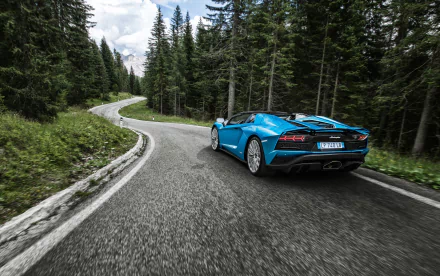 Blue Lamborghini Aventador S sports vehicle driving on a winding forest road, high-resolution 2K Quad HD PC desktop wallpaper and background.