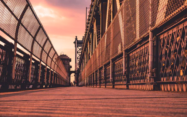 Low-angle sunset view of the man-made Manhattan Bridge in Manhattan, New York, showing the wooden walkway and steel railings — HD PC desktop wallpaper background.